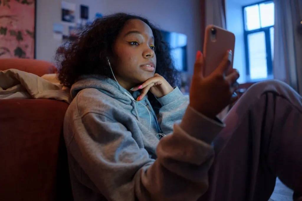 Mexico to Require Social Media Platforms to Protect Children Online Teenage girl with earphones using a smartphone indoors